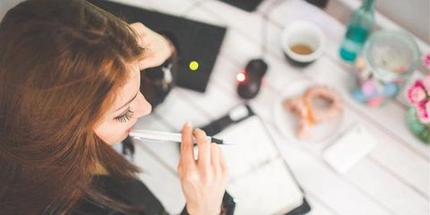 Frau sitzt an einem Schreibtisch mit einem Stift in der Hand 