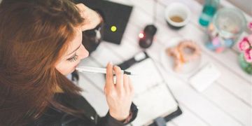 Frau sitzt an einem Schreibtisch mit einem Stift in der Hand 