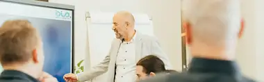 Präsentator erklärt Inhalte vor einer Gruppe von Zuhörern.
