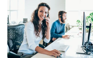 Mitarbeiterin führt ein Telefongespräch und arbeitet an ihrem Computer.
